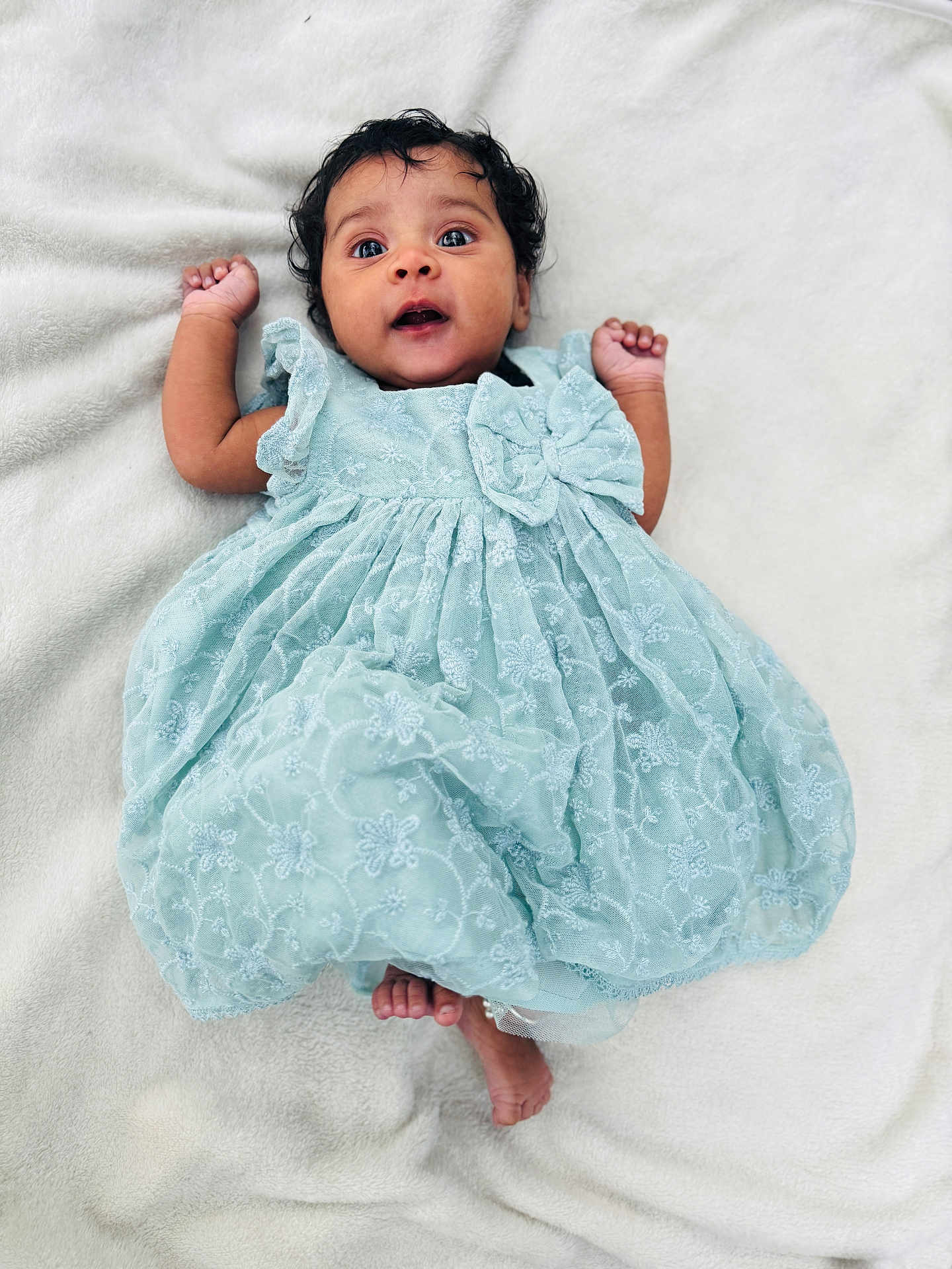 Shreevamika is registered to the contest to win money with this photo: baby, infant, child, blue_dress, lace, blanket, soft_texture, lying_down, cute, wide_eyes, expression, hands_up, bare_feet, portrait, indoors, fabric, ruffles, adorable, newborn, person