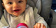 Adrien participe au concours pour gagner de l'argent avec cette photo : baby, child, high_chair, sippy_cup, red, bib, smiling, happy, face, hands, clothing, indoor, person, cute, infant, seatbelt, feeding, toy, closeup, portrait