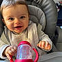 baby, child, high_chair, sippy_cup, red, bib, smiling, happy, face, hands, clothing, indoor, person, cute, infant, seatbelt, feeding, toy, closeup, portrait