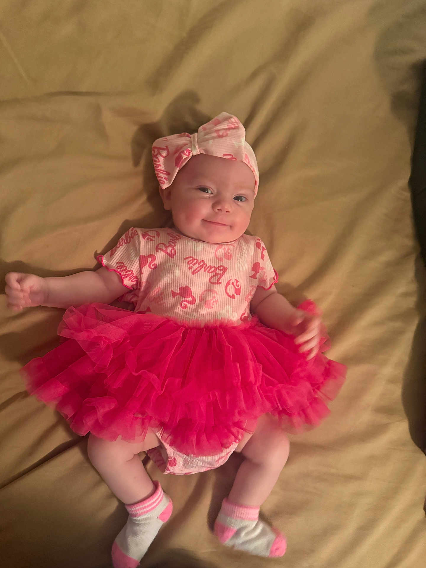 Nova is registered to the contest to win money with this photo: baby, infant, tutu, pink, headband, smile, lying_down, socks, cute, clothing, blanket, cheeky, adorable, child, person, young, fashion, happy, portrait, indoors