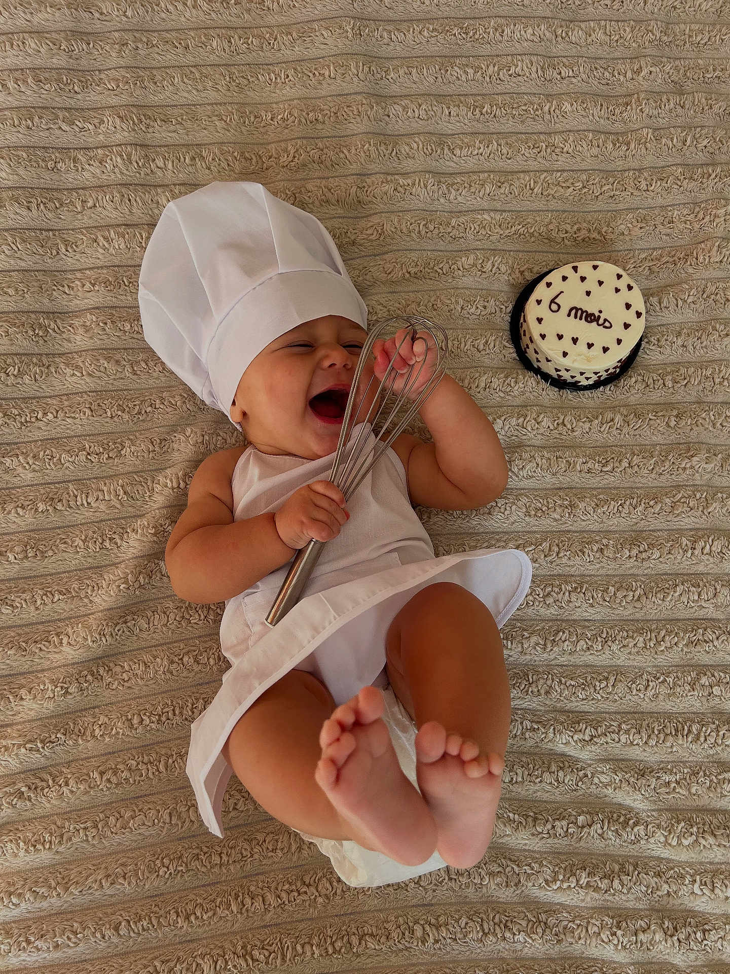 Thyam participe au concours pour gagner de l'argent avec cette photo : baby, infant, chef_hat, apron, whisk, cake, 6_months, happy, smiling, lying_down, blanket, foot, hand, cute, celebration, food, kitchen, cute_baby, portrait, child