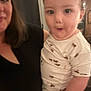 toddler, child, adult, person, indoor, clothing, white_outfit, pattern, horse_print, holding, surprised_expression, face, portrait, human, black_clothing, woman, blurred, casual, family, home