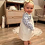toddler, child, barefoot, dress, headband, smile, indoor, wooden_floor, nursery, furniture, cabinet, crib, rug, baby, person, flooring, clothing, headwear, happy, home
