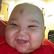 Nicholas joined the competition — help win amazing prizes! baby, smiling, close_up, face, infant, red_clothing, indoors, joyful, drool, cheeks, person, child, head, happy, expression, skin, mouth, eyes, room, light