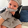 baby, child, infant, face, eyes, hat, scarf, clothing, patterned, black_and_white, sitting, couch, pillow, indoor, cute, playful, portrait, hands, legs, fashion