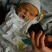 Eren participe au concours pour gagner de l'argent avec cette photo : baby, newborn, sleeping, pacifier, hat, blanket, hand, fabric, cozy, cute, infant, resting, striped_hat, wrapped, soft, indoors, human, peaceful, face, child