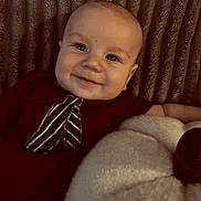Walker is registered to the contest to win money with this photo: baby, smiling, infant, portrait, indoors, plush, pumpkin, maroon_clothing, tie_design, texture, comfort, child, face, happy, cute, cozy, background, soft, young, lying_down