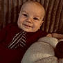 baby, smiling, infant, portrait, indoors, plush, pumpkin, maroon_clothing, tie_design, texture, comfort, child, face, happy, cute, cozy, background, soft, young, lying_down
