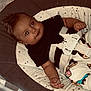 baby, baby_seat, black_shirt, cartoon_pants, child, comfort, cushion, cute, face, floor_tiles, hair, hand, indoor, infant, person, portrait, relaxed, seatbelt, smiling, young