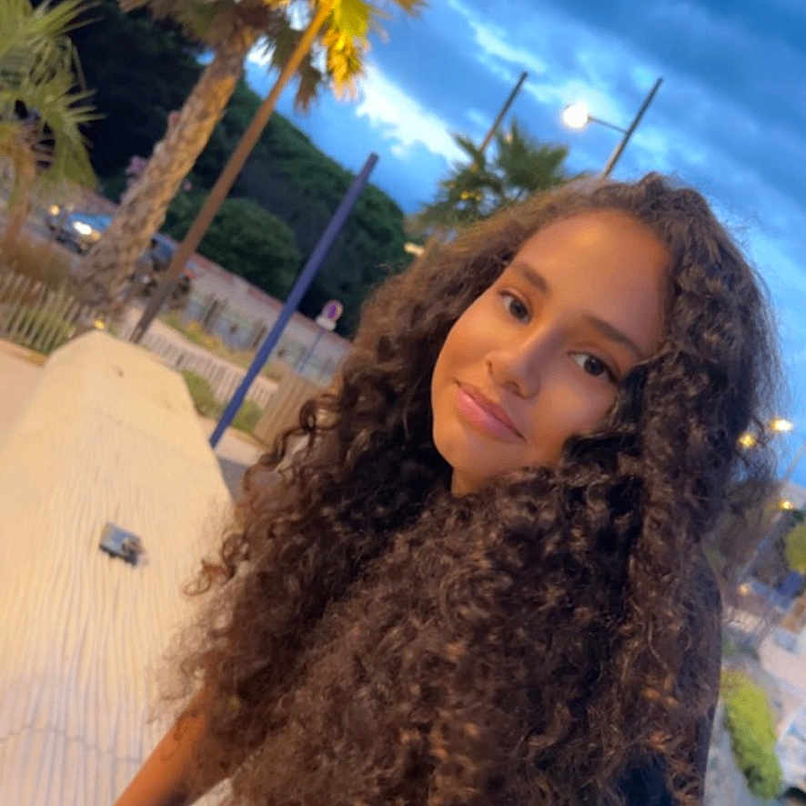 Ilhem participe au concours pour gagner de l'argent avec cette photo : bench, black_shirt, casual, cloudy_sky, curly_hair, evening, girl, happy, jeans, nature, outdoor, palm_tree, park, portrait, relaxation, scenery, smile, street_lamp, twilight, young_person