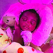 Wynter is registered to the contest to win money with this photo: baby, sleeping, blanket, cherry_pattern, plush_toy, bunny, crib, netting, pillow, child, infant, cute, rest, soft, cozy, indoors, purple_light, peaceful, face, hand