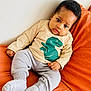 baby, child, infant, sitting, couch, orange, clothing, shirt, dinosaur, pants, socks, indoors, cute, portrait, face, expression, relaxed, furniture, cozy, wall