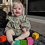 baby, child, smiling, sitting, toy_blocks, indoor, carpet, colorful, cute, face, person, clothing, happy, playtime, floor, toddler, home, soft_texture, young_child, portrait