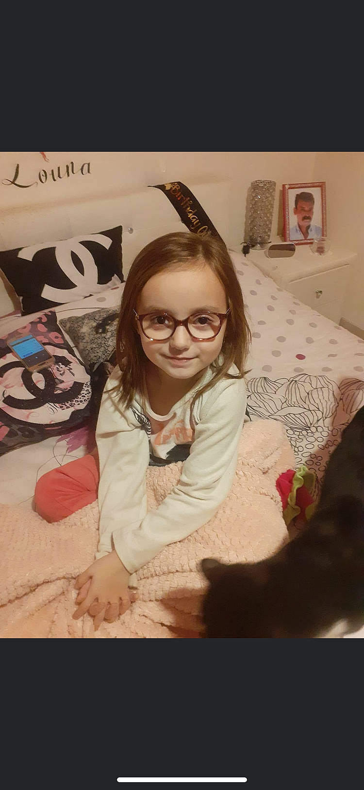 Liana participe au concours pour gagner de l'argent avec cette photo : child, comfort, event, eyewear, flooring, fun, glasses, happy, joy, laugh, linens, long_hair, pattern, person, picture_frame, portrait_photography, room, sitting, sleeve, smile