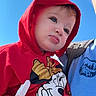 toddler, child, hoodie, red_clothing, minnie_mouse, cartoon_character, blue_sky, outdoor, daylight, face, person, cute, baby, infant, casual_clothing, portrait, expression, young_child, fashion, closeup