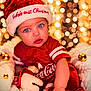 Amani is registered to the contest to win money with this photo: baby, infant, child, santa_hat, christmas, holiday, bokeh, string_lights, red_clothing, blue_eyes, plush_toy, ornament, cozy_blanket, portrait, closeup, festive, seasonal_decor, cute, sitting, studio_lighting