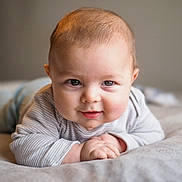 Sebastian joined the competition — help win amazing prizes! baby, infant, child, portrait, smiling, lying_down, tummy_time, face, eyes, hands, long_sleeves, striped_clothing, bed, blanket, bedroom, indoors, soft_lighting, close_up, photography, happy