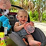 Adalynn is registered to the contest to win money with this photo: baby, car_seat, sippy_cup, smile, outdoor, palm_trees, sunny, blue_sky, greenery, tablecloth, floral_pattern, child, infant, toy, seatbelt, summer, happy, person, nature, foot