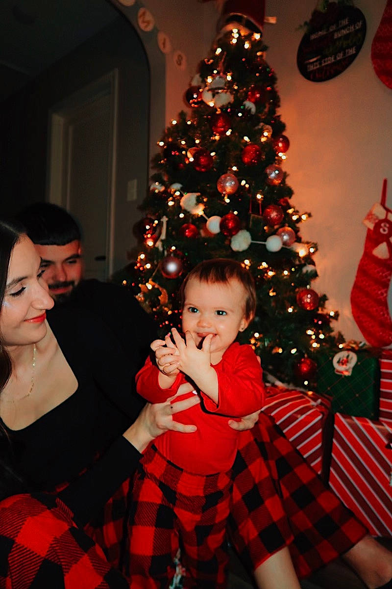 Aubrey is registered to the contest to win money with this photo: black, christmas, christmas_decoration, christmas_ornament, christmas_tree, event, fun, happy, head, holiday_ornament, joy, people, person, plaid, plant, red, smile, standing, tartan, toddler