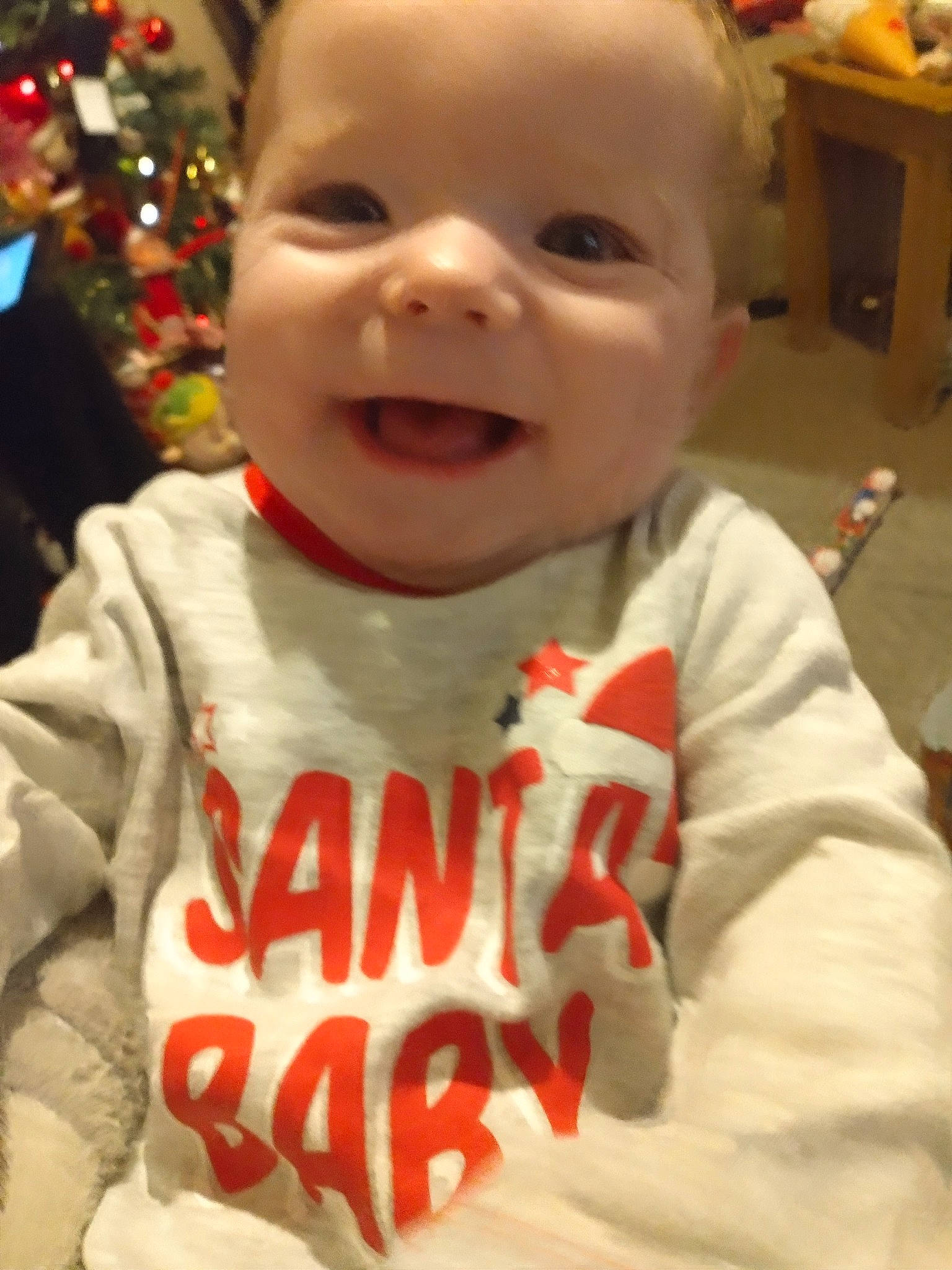 Ellie is registered to the contest to win money with this photo: baby, cheek, chin, christmas_tree, eye, face, facial_expression, forehead, hairstyle, happy, head, human_body, lip, mouth, nose, organ, person, skin, sleeve, smile