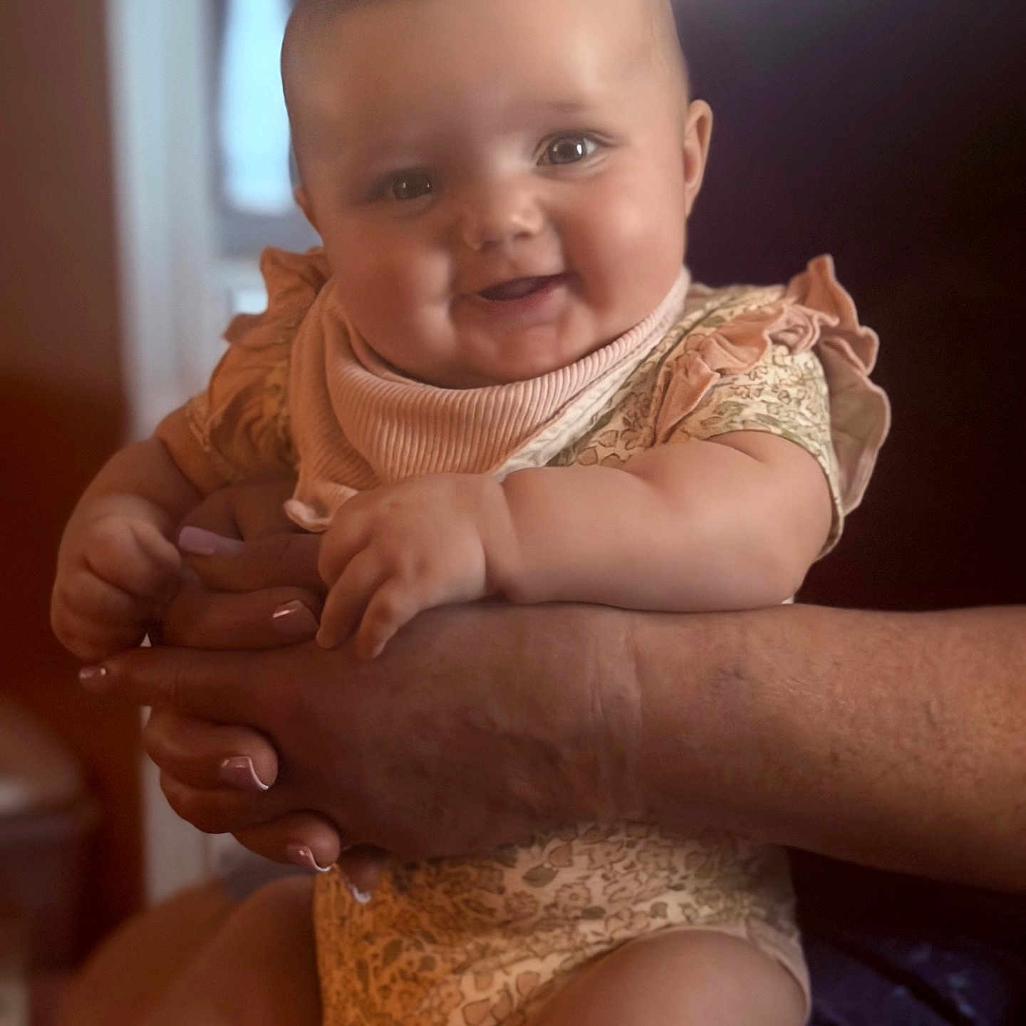 Sophia joined the competition — help win amazing prizes! baby, child, smile, arms, person, clothing, indoor, portrait, hands, bib, cute, infant, happy, skin, face, sitting, holding, warm_light, closeup, human