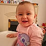 baby, child, smiling, pink_sweatshirt, high_chair, indoor, toys, cartoon_character, happy, face, person, clothing, home, furniture, cute, infant, table, sitting, young_child, portrait