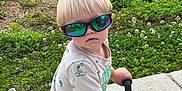 Laken joined the competition — help win amazing prizes! toddler, child, sunglasses, toy_vehicle, outdoor, grass, greenery, shorts, tshirt, blond_hair, summer, sunny, play, side_view, concrete, young_child, casual, reflection, hands_on_handlebars, cute