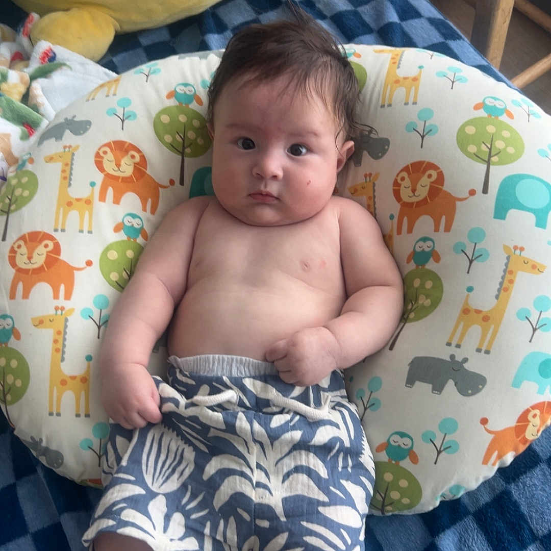 Chantico is registered to the contest to win money with this photo: animal_pattern, baby, bed, blue_blanket, child, comfort, cute, expression, face, furniture, indoor, infant, person, pillow, plush_toy, room, shorts, skin, socks, wooden_chair