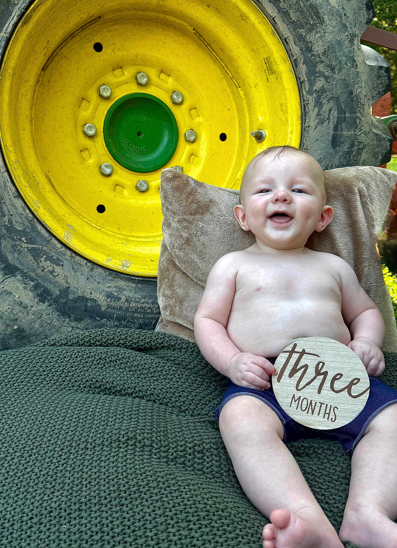 Jace joined the competition — help win amazing prizes! baby, infant, smiling, shirtless, shorts, wooden_sign, three_months, blanket, pillow, outdoor, tractor_wheel, yellow, green, rustic, summer, cute, child, feet, happy, portrait