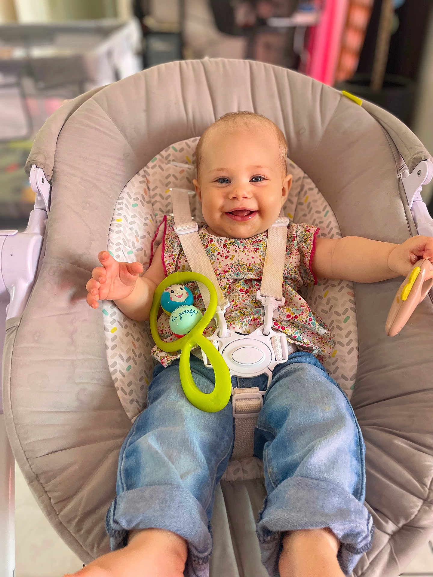 Rose a rejoint le concours — aidez-le/la à gagner de superbes lots ! baby, child, smiling, happy, sitting, baby_seat, toy, colorful_toy, clothing, jeans, floral_top, indoor, person, cute, infant, face, hands, footwear, strap, comfort