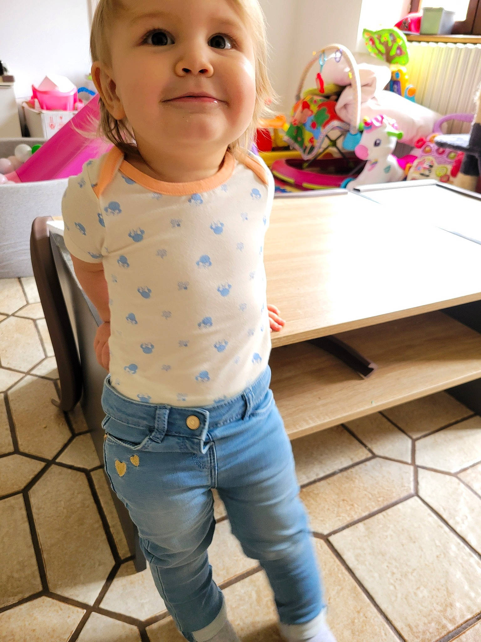 Elena participe au concours pour gagner de l'argent avec cette photo : baby, baby_toddler_clothing, cheek, clothing, face, floor, flooring, happy, head, jeans, joy, leg, neck, person, skin, sleeve, standing, toddler, trunk, waist