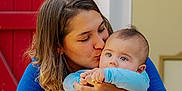 Xanti participe au concours pour gagner de l'argent avec cette photo : woman, baby, kiss, blue_clothing, red_door, emotional, love, affection, portrait, closeup, face, skin, hair, hands, indoor, family, tender, candid, person, child