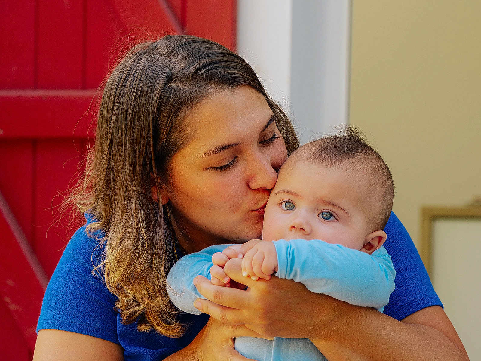 Xanti participe au concours pour gagner de l'argent avec cette photo : woman, baby, kiss, blue_clothing, red_door, emotional, love, affection, portrait, closeup, face, skin, hair, hands, indoor, family, tender, candid, person, child