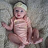 Elora joined the competition — help win amazing prizes! baby, infant, headband, onesie, blanket, fluffy, cute, child, skin, foot, hand, expression, portrait, indoors, soft_texture, pink_clothing, flower_print, lying_down, curious, young