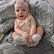 Elora joined the competition — help win amazing prizes! baby, infant, child, blanket, headband, flower, smiling, cute, soft_texture, indoors, sitting, happy, pink_clothing, feet, hands, cozy, portrait, face, young, nursery
