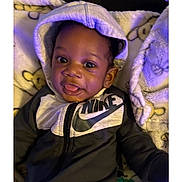 Royal is registered to the contest to win money with this photo: baby, child, hoodie, nike, blanket, smile, tongue_out, cute, infant, clothing, indoors, portrait, happy, cozy, soft, young_child, face, sitting, baby_garment, casual