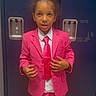 background, boy, child, clothing, curly_hair, expression, fashion, formal_wear, hands, indoor, locker, person, pink_suit, portrait, school, serious, standing, suit, tie, young