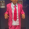 bright_colors, child, clothing, confident, curly_hair, door, expression, fashion, formal_wear, indoor, jacket, locker, pants, person, pink_suit, portrait, standing, tie, white_shirt, young