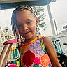 beads, braids, child, colorful_dress, cute, daylight, fence, fruit_pattern, girl, happy, house, outdoor, play, porch, portrait, smile, summer, toys, tree, young
