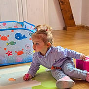 Kécya a rejoint le concours — aidez-le/la à gagner de superbes lots ! baby, child, colorful, curious, cute, floor, furniture, indoor, light, mat, pants, person, pigtails, pink_shoes, playing, room, shirt, toddler, toy, wooden_floor