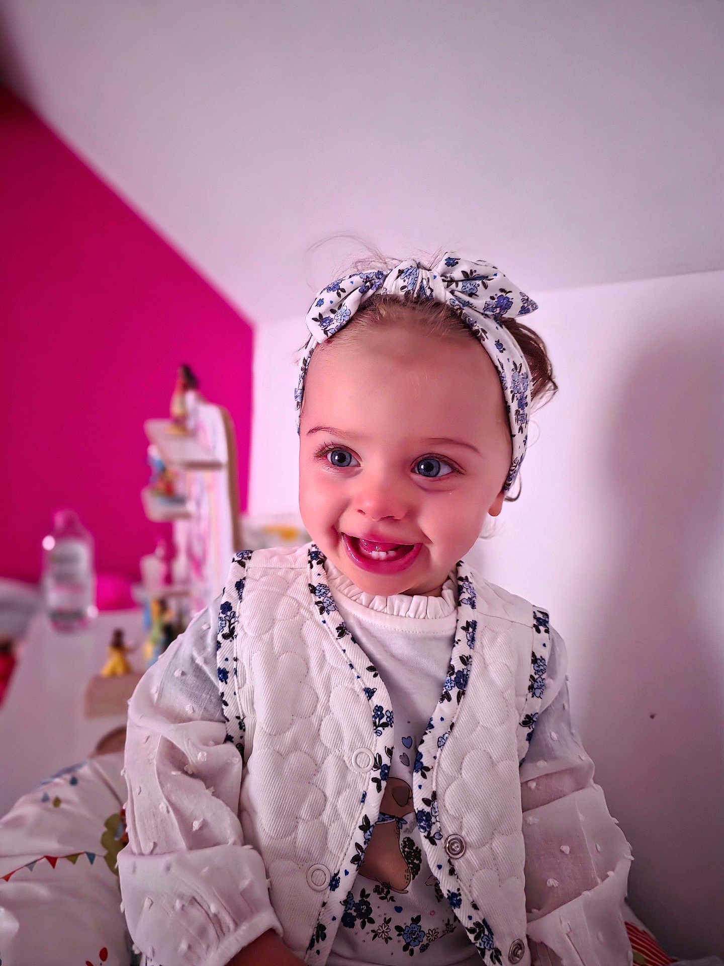 Kécya a rejoint le concours — aidez-le/la à gagner de superbes lots ! toddler, child, smiling, headband, vest, white_clothing, blue_eyes, indoor, portrait, happy, cute, baby, fashion, blurry_background, magenta_wall, person, face, apparel, female, infant