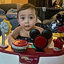 baby, child, walker, toy, disney, mickey_mouse, indoor, curious, face, furniture, blanket, couch, home, floor, playtime, infant, person, cute, decorations, colorful