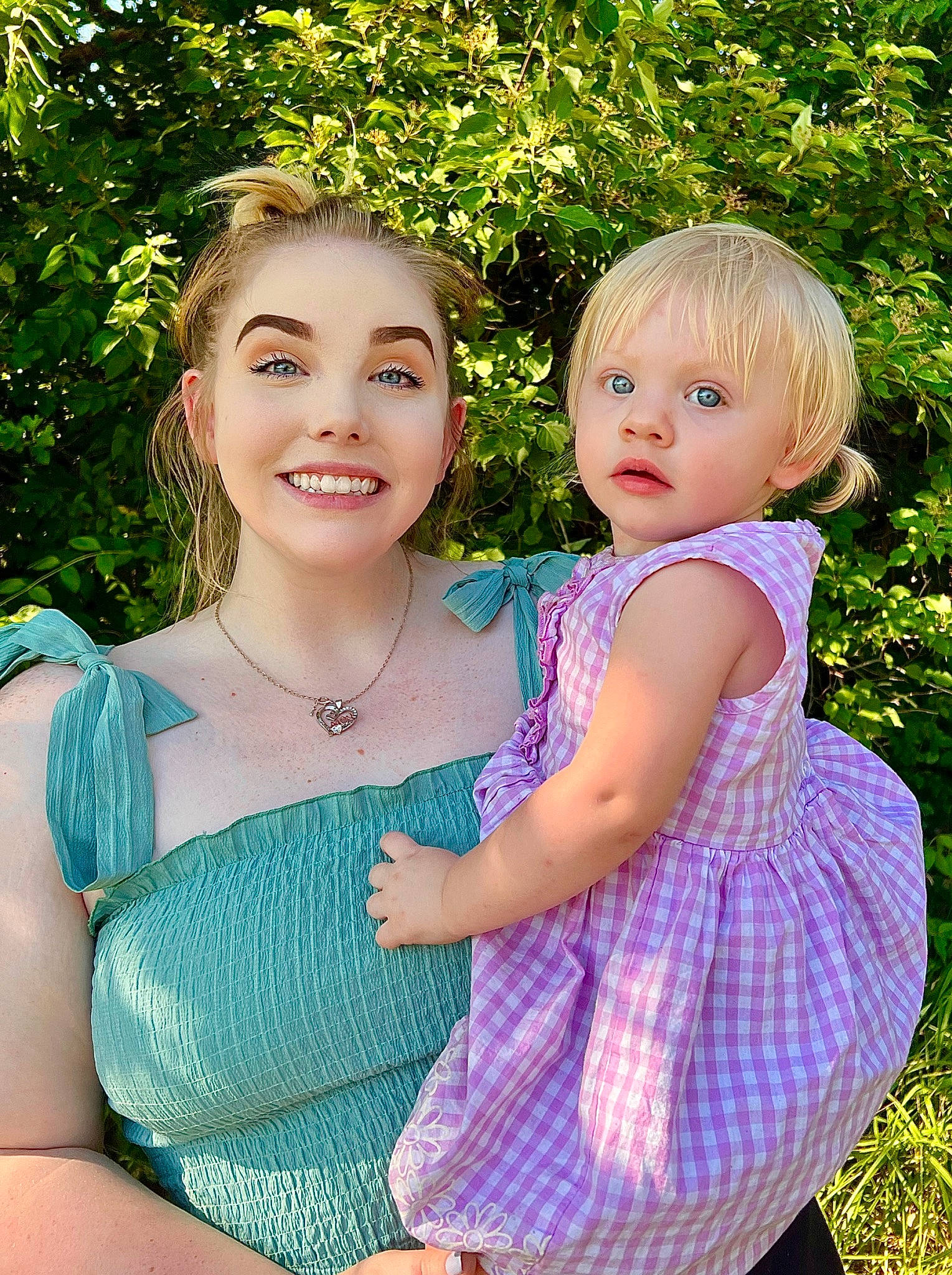 Hailey is registered to the contest to win money with this photo: blond, child, dress, event, face, formal_wear, fun, gesture, grass, green, happy, iris, joy, leisure, people_in_nature, person, pink, plant, smile, toddler