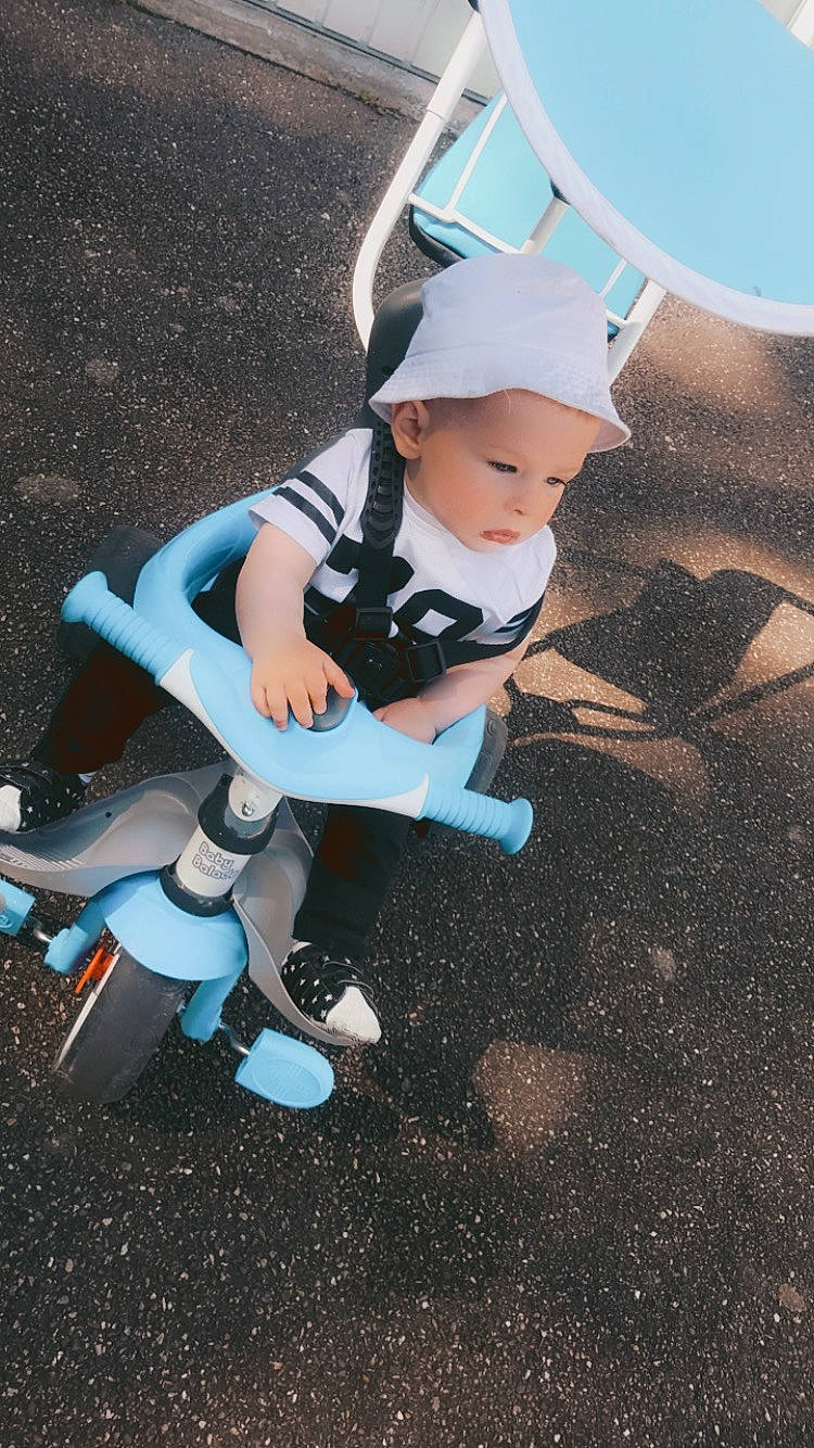 Keyden participe au concours pour gagner de l'argent avec cette photo : asphalt, automotive_wheel_system, baby, baby_products, baby_toddler_clothing, baseball_cap, electric_blue, fun, grass, hat, headwear, human_leg, person, play, recreation, shadow, sitting, sky, soil, t_shirt
