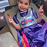 child, girl, car_seat, purple_dress, peace_sign, smiling, ribbons, sparkles, interior, vehicle, happy, portrait, fashion, seatbelt, cute, young, casual, colorful, sitting, hand_gesture