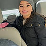 child, smiling, car_interior, winter_clothing, hat, jacket, seat, braces, person, young, happy, window, seatbelt, indoor, casual, portrait, face, gloves, long_hair, travel