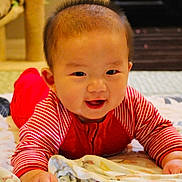 Arthur is registered to the contest to win money with this photo: baby, child, smiling, red_clothing, striped_sleeves, blanket, indoor, cute, portrait, face, happy, infant, toddler, hands, lying_down, cozy, soft_lighting, home, floor, playtime