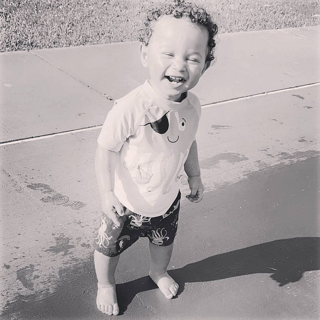 Carter joined the competition — help win amazing prizes! baby, black, black_and_white, cool, eyewear, face, fun, hairstyle, happy, monochrome, person, photograph, sand, shorts, sleeve, smile, standing, style, t_shirt, toddler