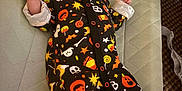 Aubriella is registered to the contest to win money with this photo: baby, infant, onesie, halloween, costume, lying_down, face, clothing, pattern, cute, padded_mat, carpet, hand, smile, indoor, person, newborn, head, sleepwear, baby_girl