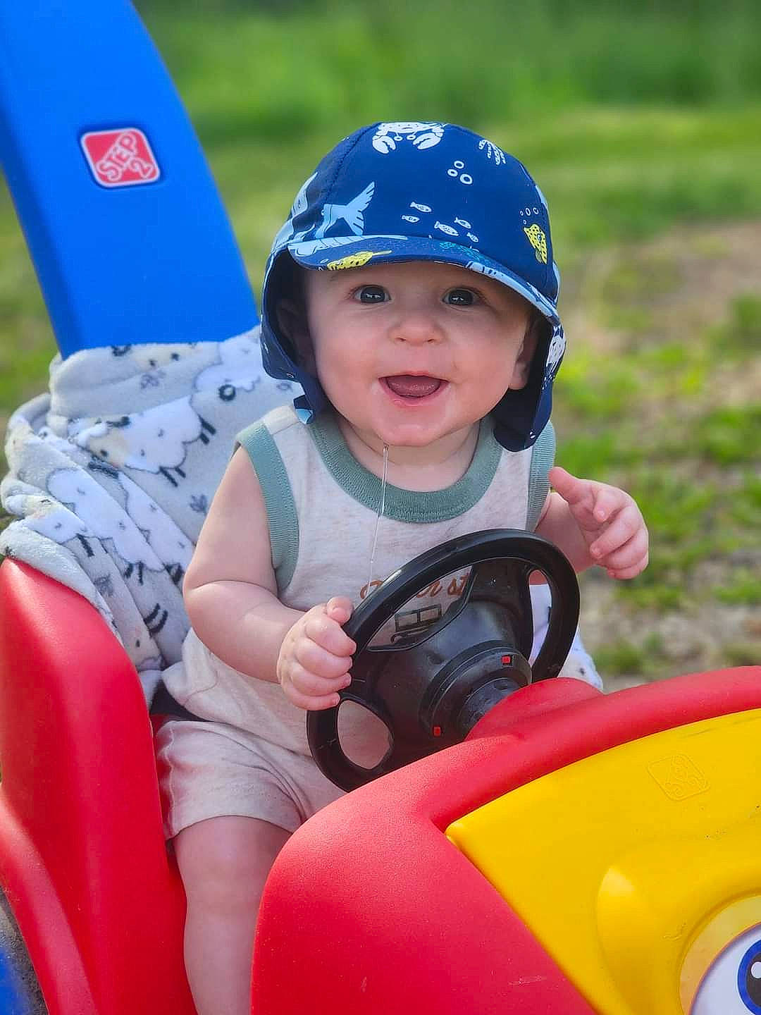 Bryar is registered to the contest to win money with this photo: automotive_design, automotive_exterior, automotive_tire, baseball_cap, child, electric_blue, fun, grass, happy, headgear, headwear, helmet, leisure, motor_vehicle, outdoor_recreation, person, personal_protective_equipment, recreation, riding_toy, smile